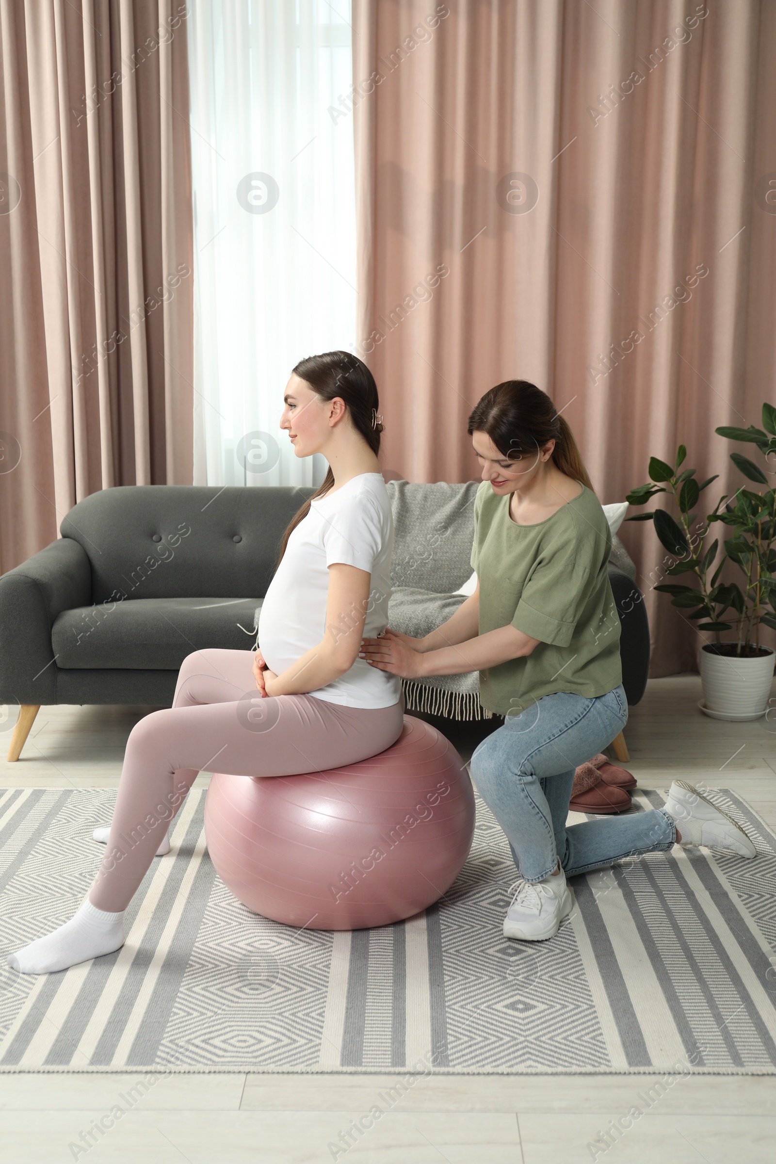 Photo of Doula massaging pregnant woman at home. Preparation for child birth