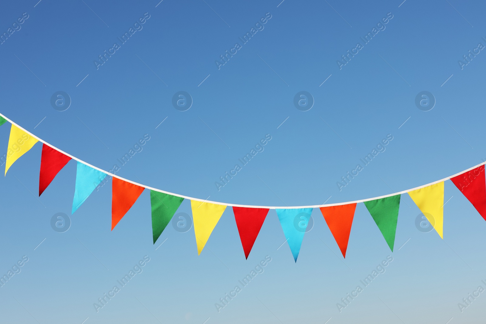 Photo of Bunting with colorful triangular flags against blue sky