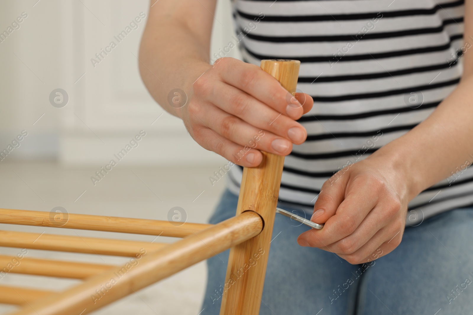 Photo of Woman with hex key assembling furniture indoors, closeup
