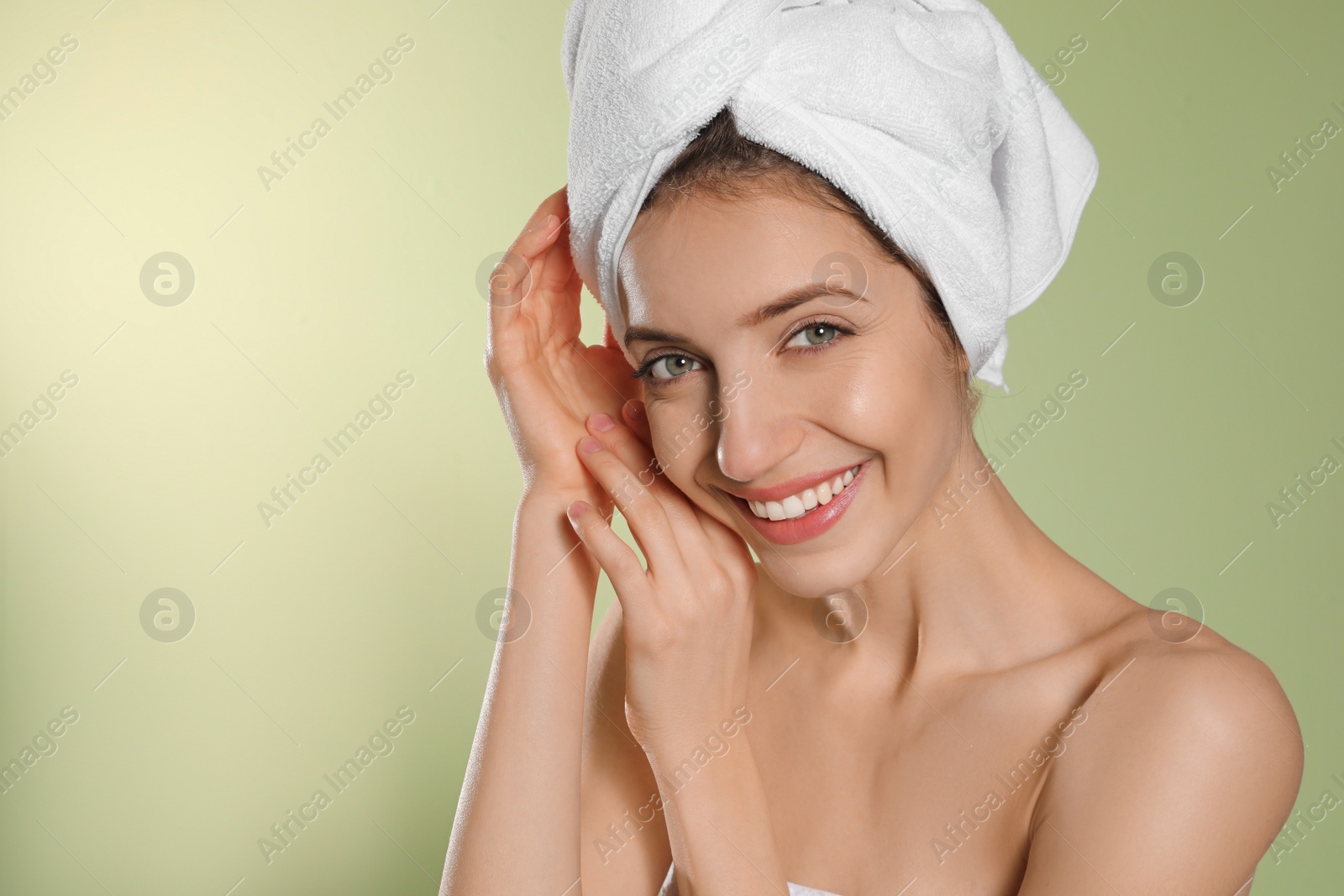 Photo of Beautiful young woman with hair wrapped in towel after washing on light green background