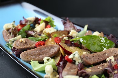 Photo of Delicious salad with beef tongue and cheese on black table, closeup