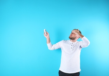 Photo of Young man suffering from heat on color background with copy space text. Air conditioner malfunction