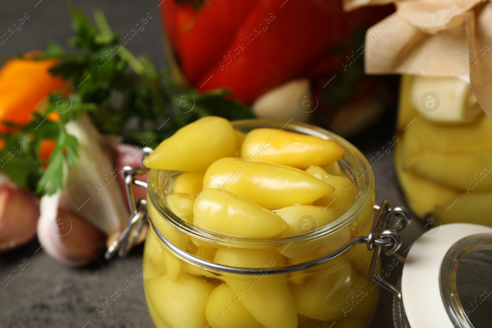 Photo of Glass jar with pickled peppers on grey table