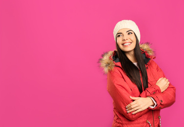 Happy young woman in warm clothes on pink background, space for text. Winter vacation