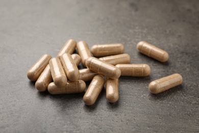 Photo of Dietary supplement capsules on grey table, closeup