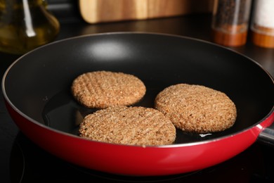 Photo of Cooking vegan cutlets in frying pan on cooktop, closeup