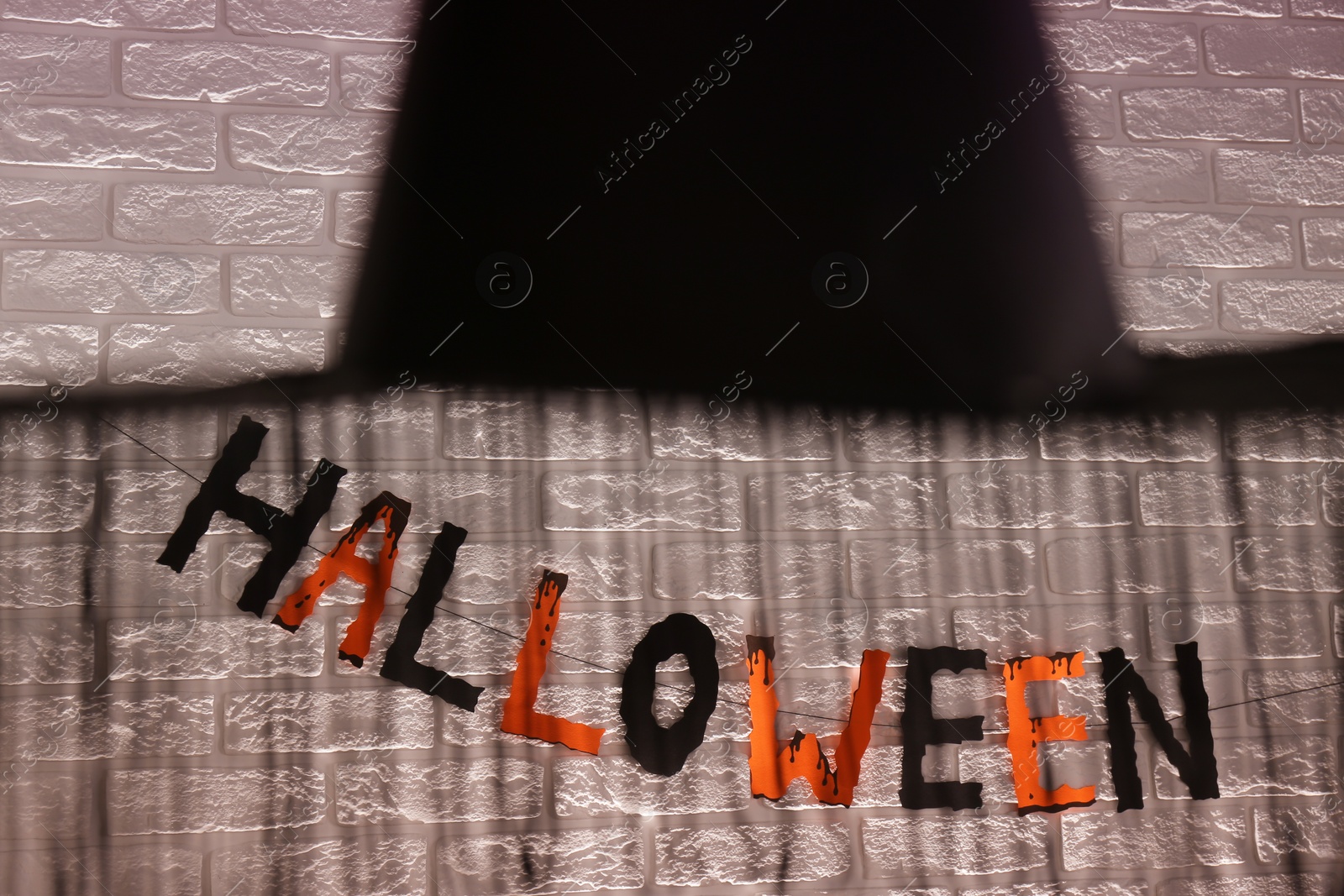 Photo of Word Halloween made of colorful letters and festive decor on brick wall