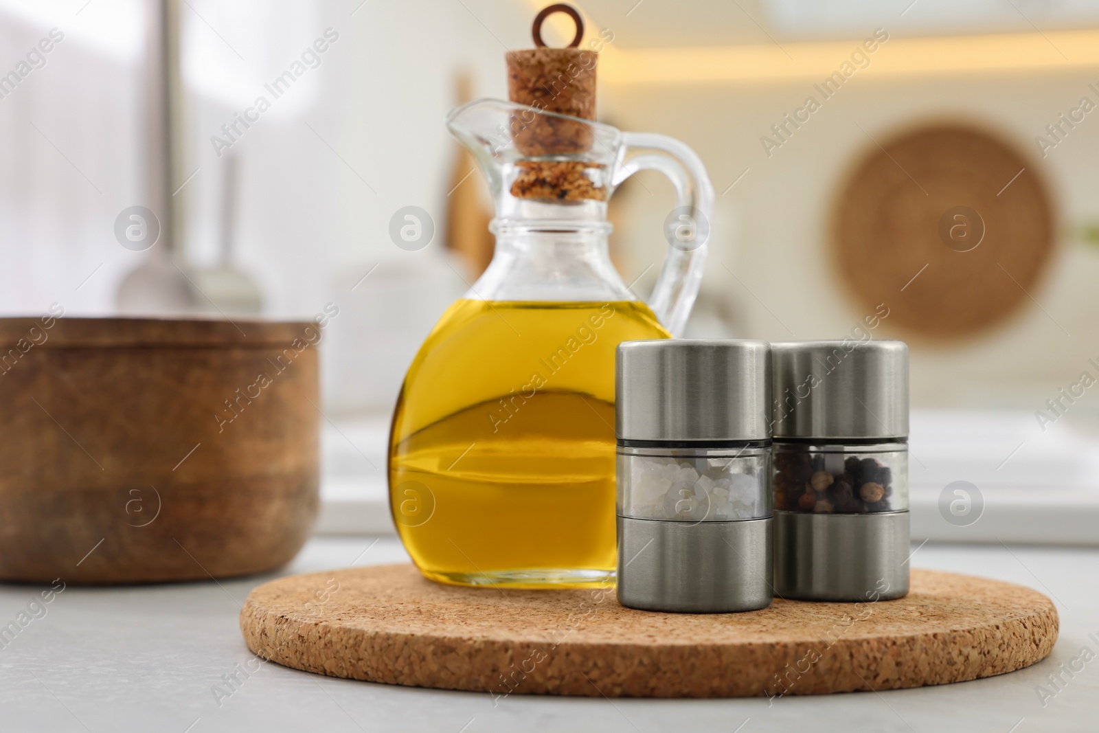 Photo of Salt and pepper mills with bottle of oil on table in kitchen