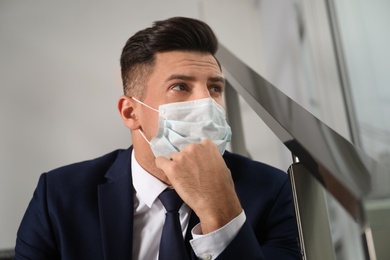 Photo of Sad man in protective mask indoors. Self-isolation during coronavirus pandemic