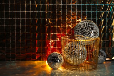 Photo of Many shiny disco balls on floor near foil party curtain. Space for text