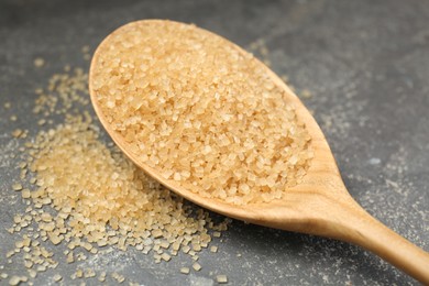 Photo of Spoon with brown sugar on grey textured table, closeup