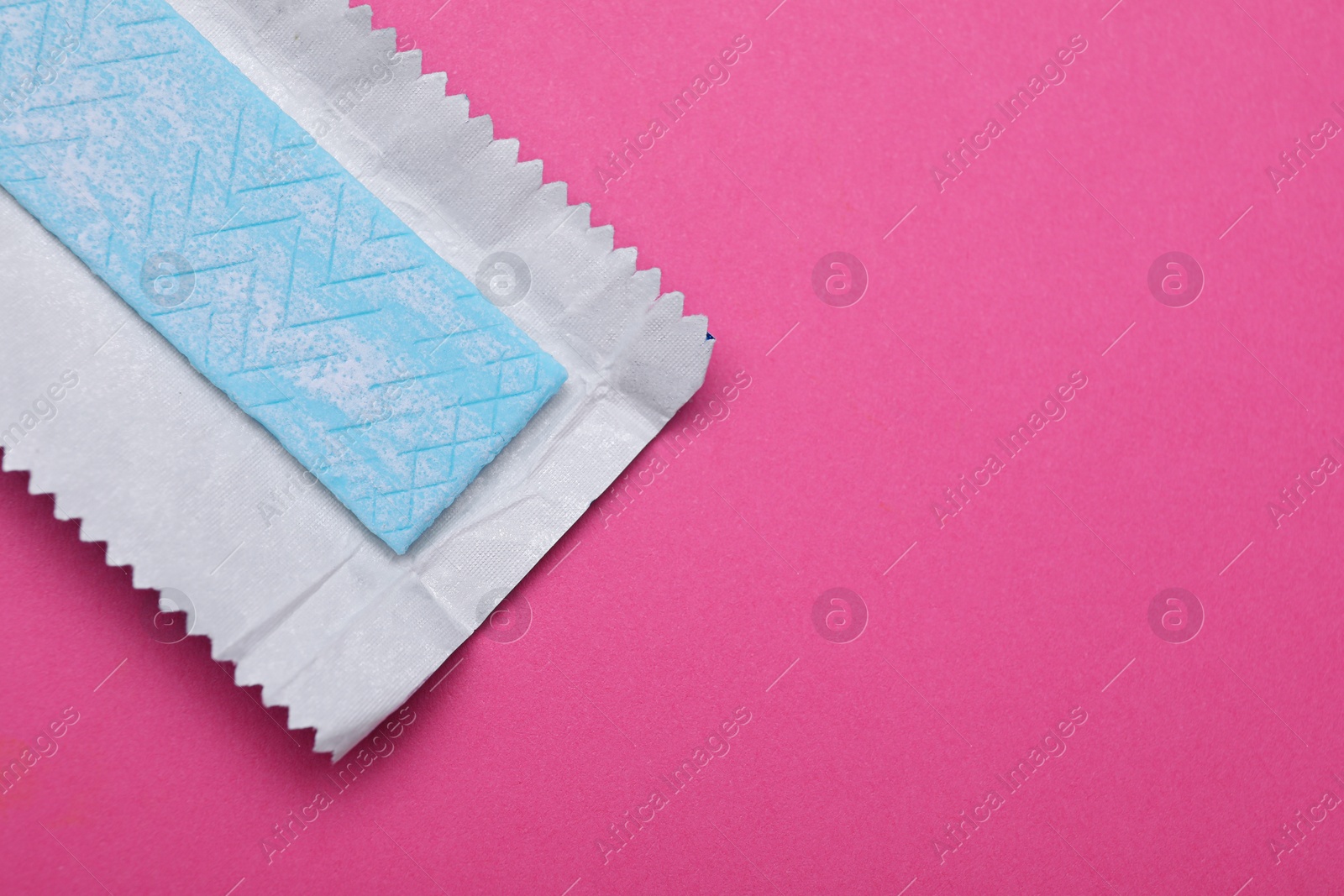 Photo of Unwrapped stick of tasty chewing gum on bright pink background, top view. Space for text