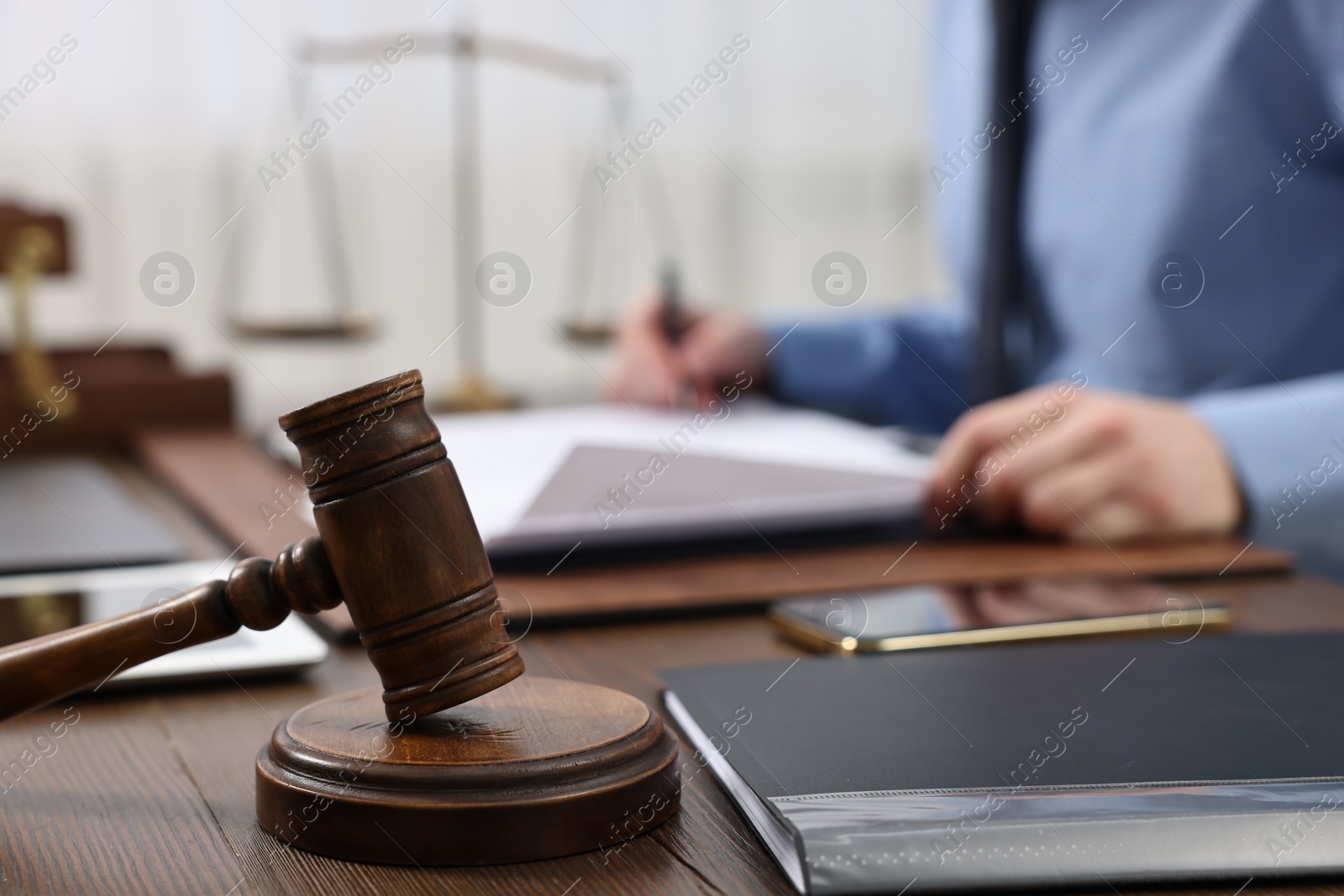 Photo of Lawyer working with documents at wooden table, focus on gavel