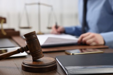 Lawyer working with documents at wooden table, focus on gavel