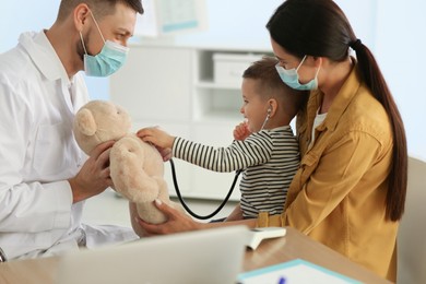 Photo of Mother and son visiting pediatrician in hospital. Doctor playing with little boy
