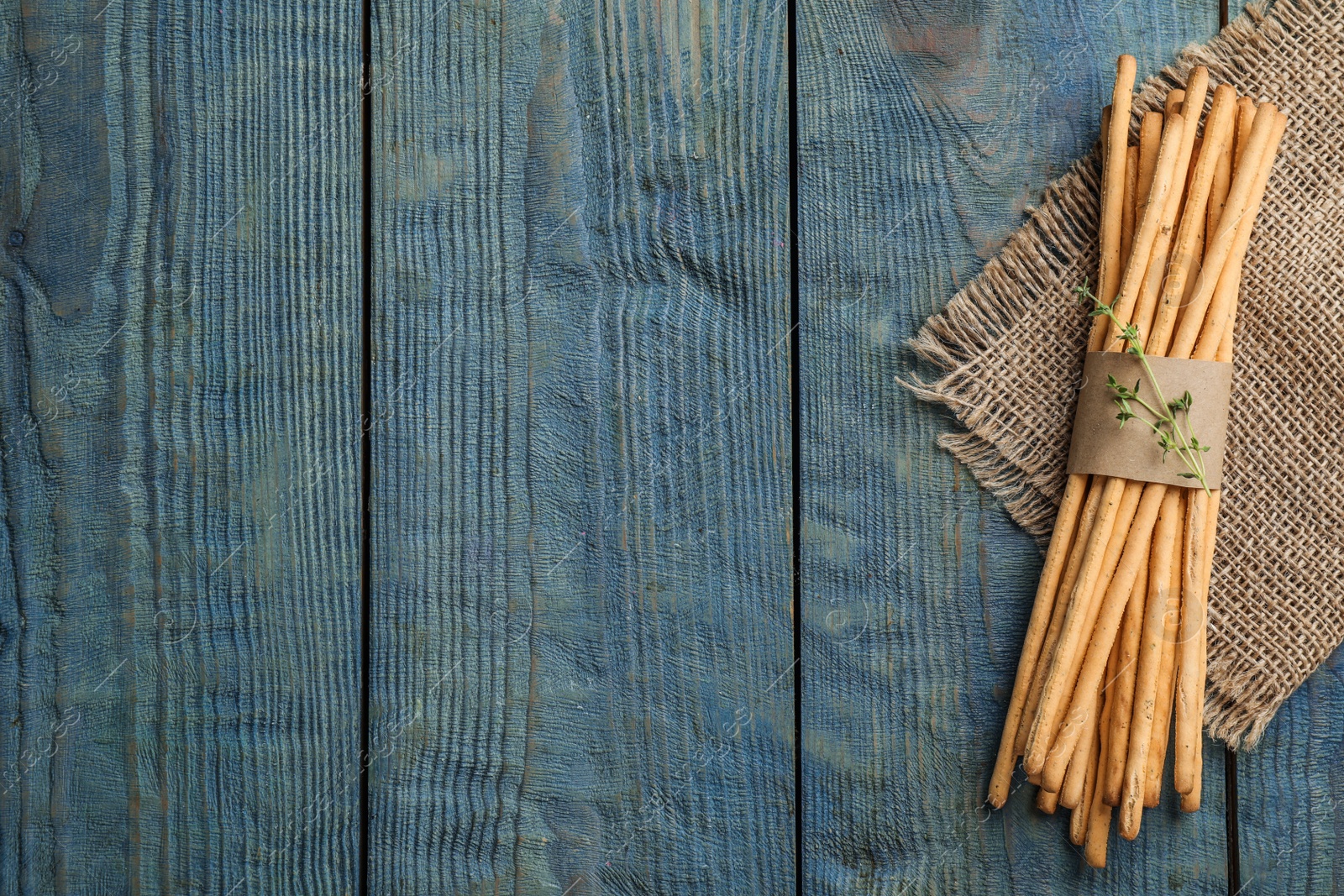 Photo of Delicious grissini sticks with thyme on wooden table, top view. Space for text