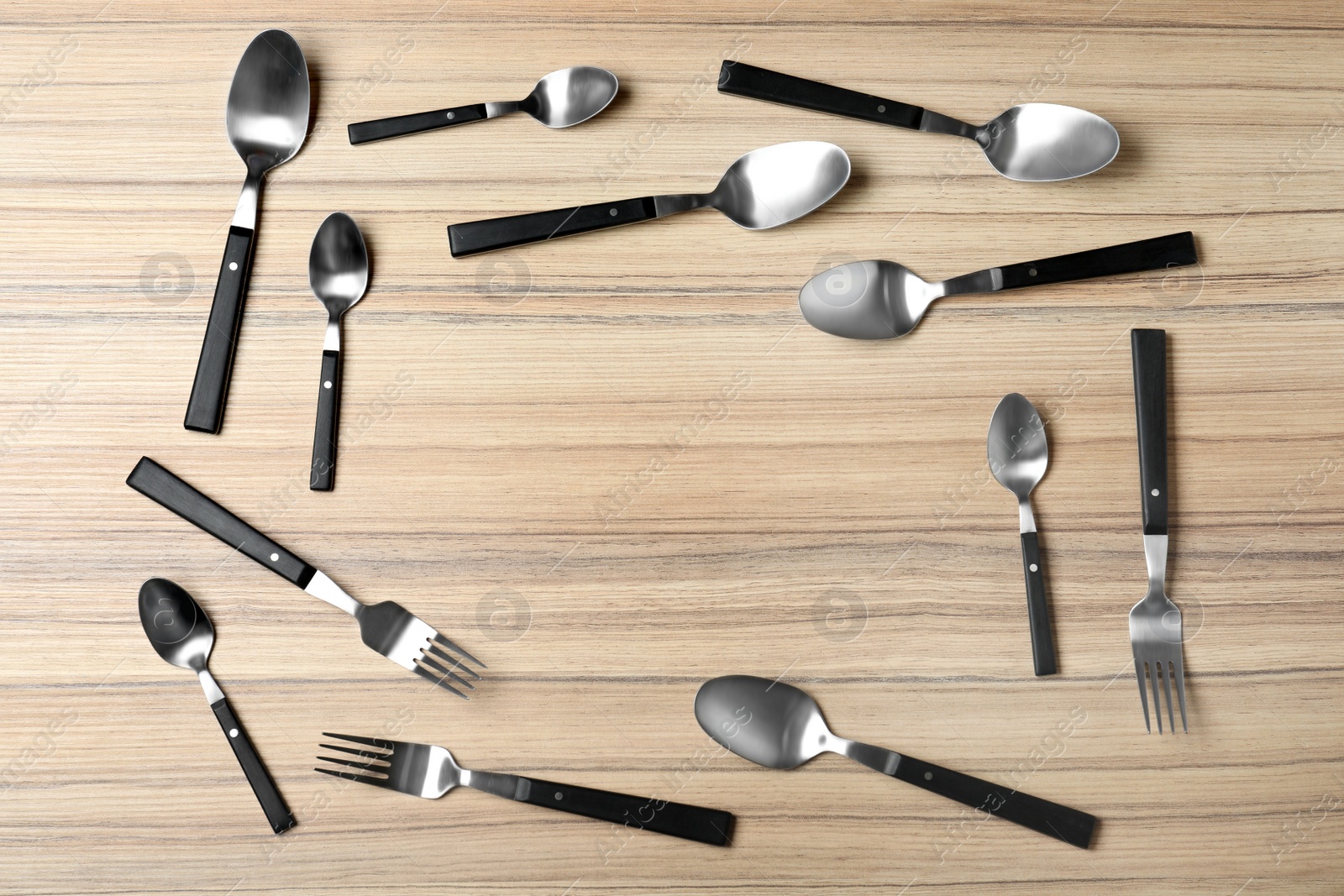 Photo of Frame made of new cutlery on wooden table, flat lay with space for text