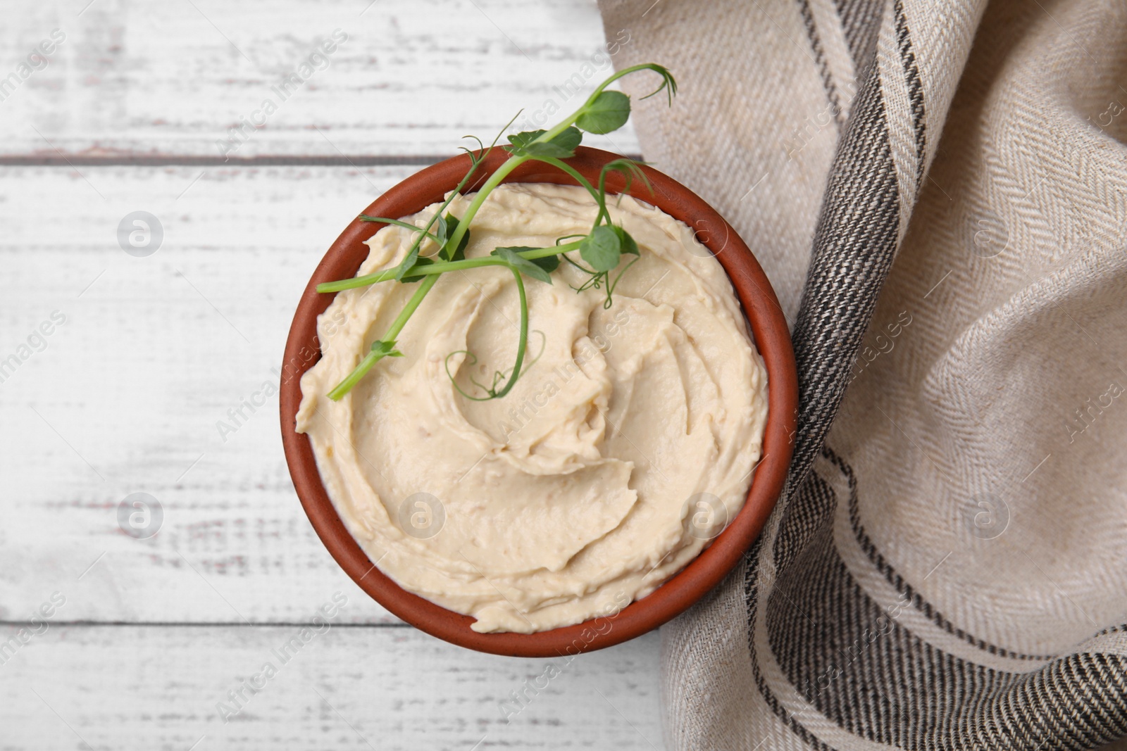 Photo of Bowl with delicious hummus on white wooden table, flat lay