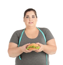 Photo of Overweight woman with hamburger and measuring tape on white background