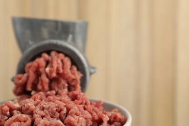 Photo of Mincing beef with manual meat grinder on blurred background, closeup. Space for text