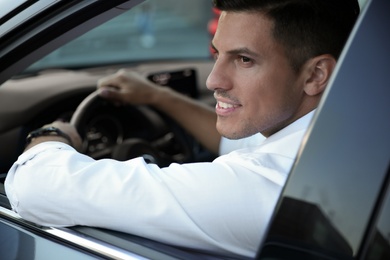 Photo of Handsome man in his modern car, view from outside