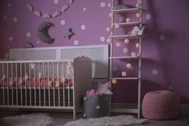 Photo of Baby room interior with crib near color wall