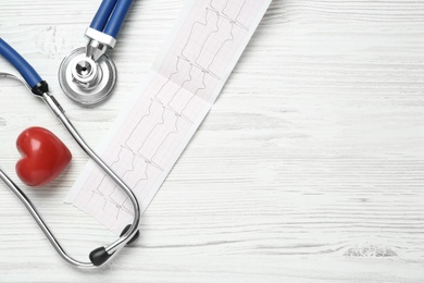 Cardiogram report, red heart and stethoscope on white wooden table, flat lay. Space for text