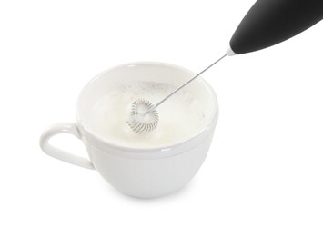 Photo of Whisking milk in cup with mini mixer (frother wand) isolated on white