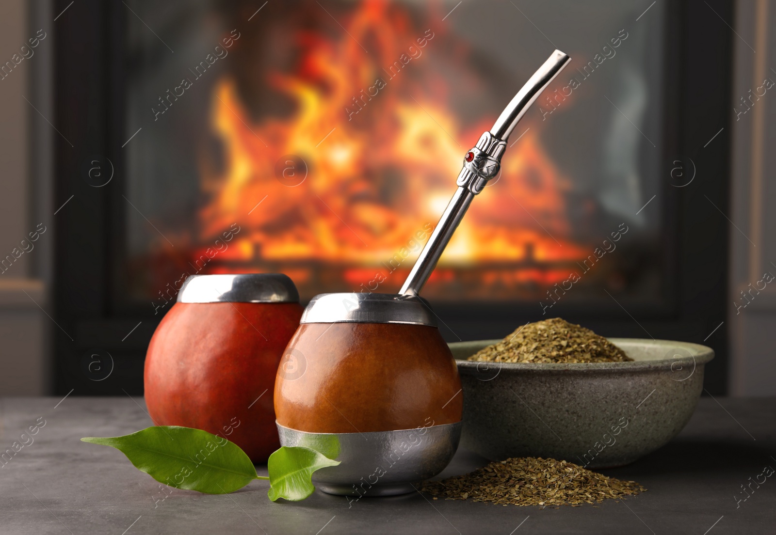 Image of Calabashes with mate tea and bombilla on light grey table near fireplace