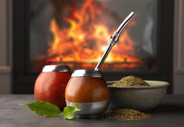 Image of Calabashes with mate tea and bombilla on light grey table near fireplace