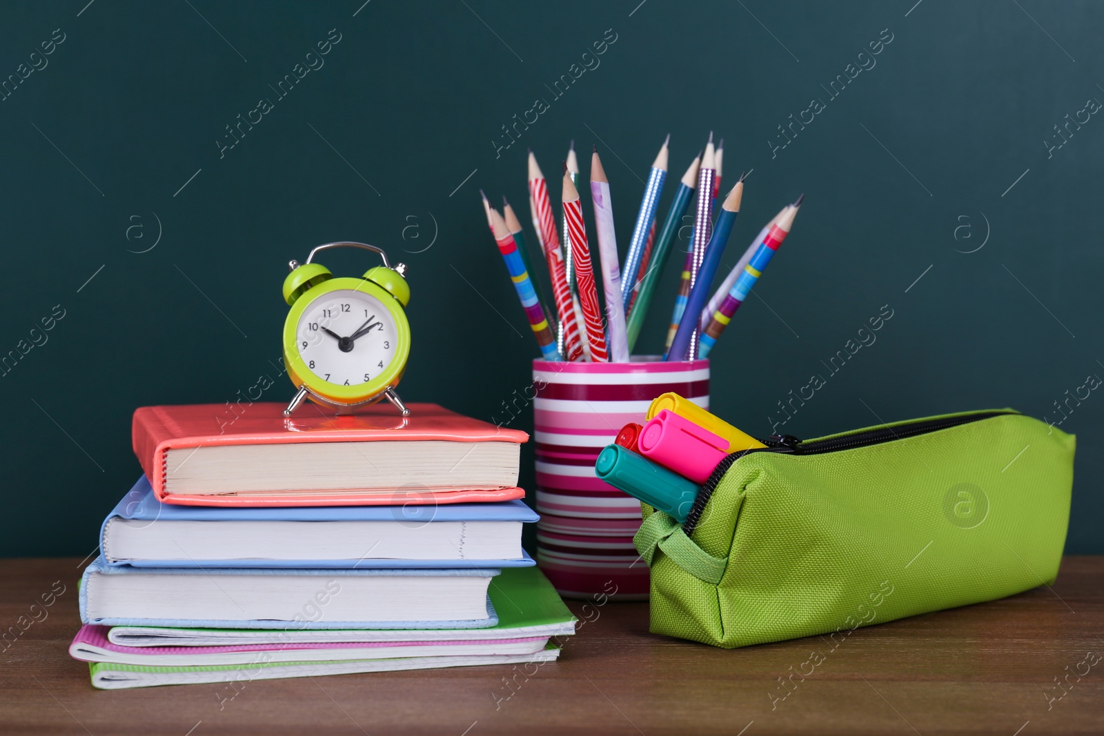 Photo of Composition with stationery and alarm clock on table near chalkboard. Doing homework