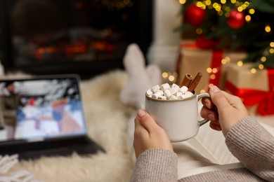 Photo of Woman drinking delicious cocoa and watching Christmas movie at home, closeup. Space for text