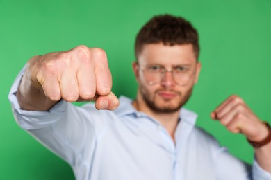 Photo of Young man ready to fight against green background, focus on hand. Space for text
