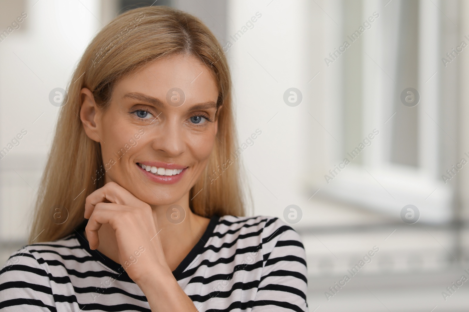 Photo of Portrait of beautiful woman with blonde hair. Attractive lady smiling and looking into camera. Space for text