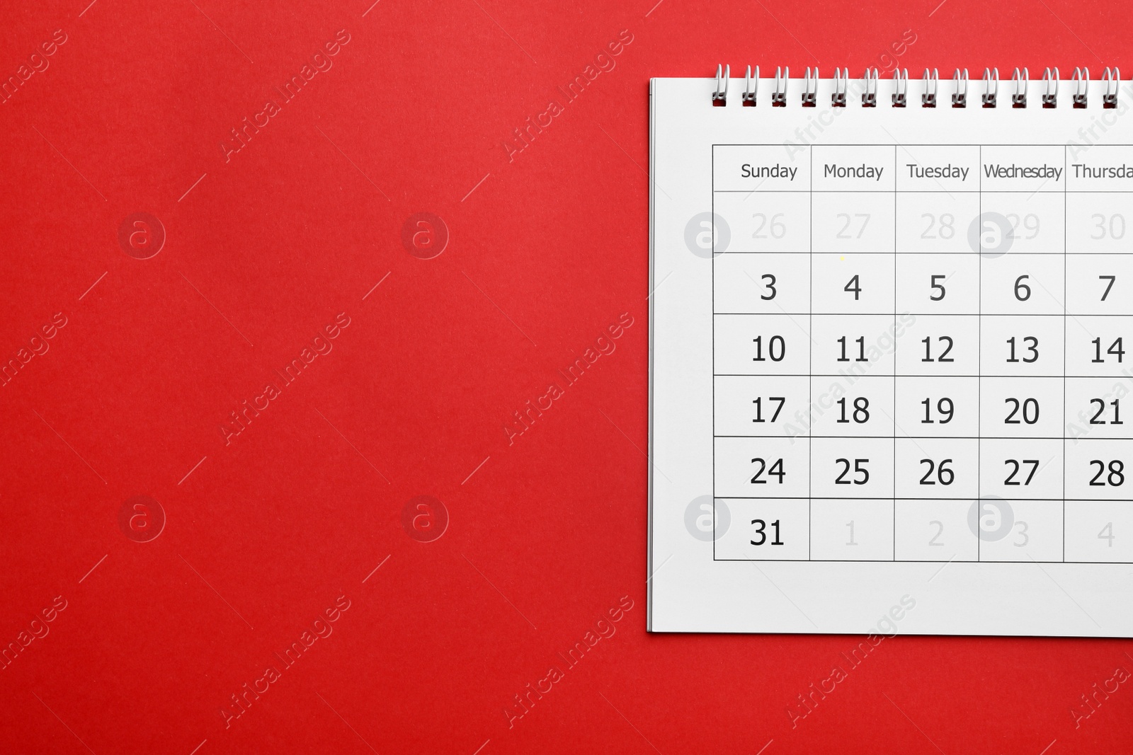 Photo of Paper calendar on red background, top view. Space for text