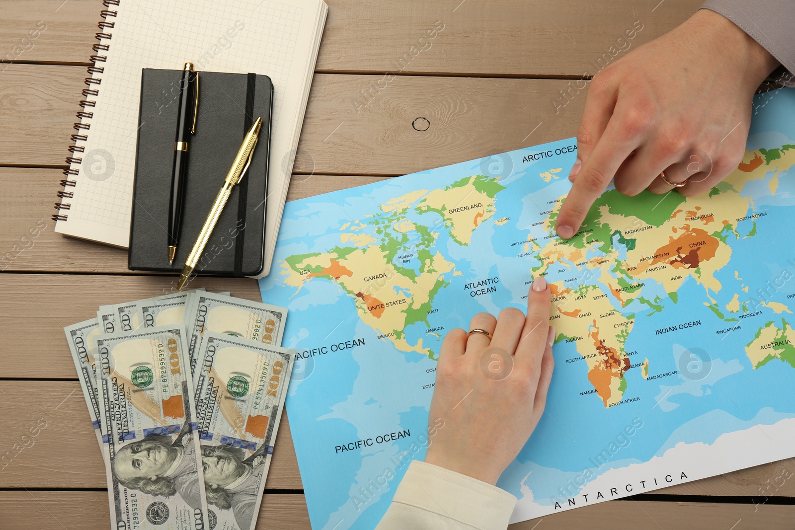 Photo of Man and woman planning their honeymoon trip with world map at wooden table, top view