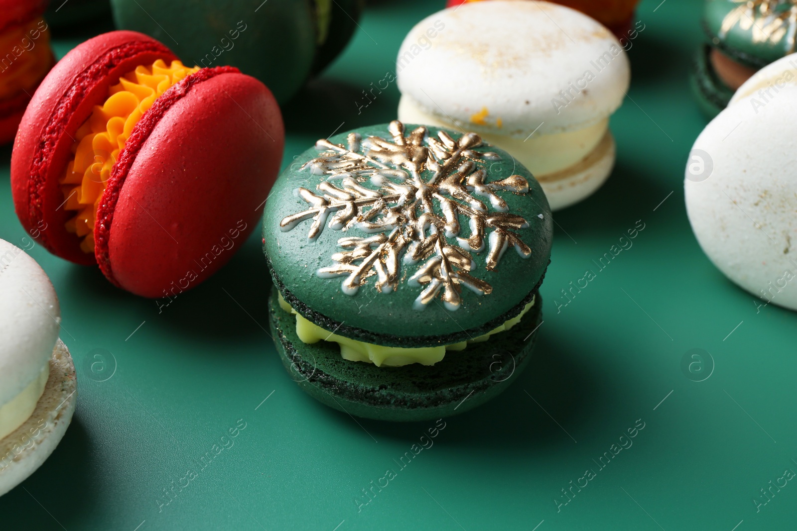 Photo of Beautifully decorated Christmas macarons on green background, closeup