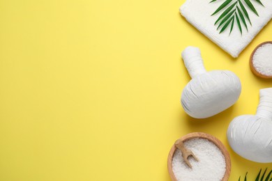 Beautiful spa composition with herbal massage bags and different care products on yellow background, flat lay. Space for text