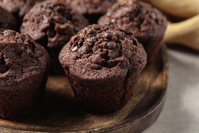 Photo of Board with delicious chocolate muffins on light table, closeup