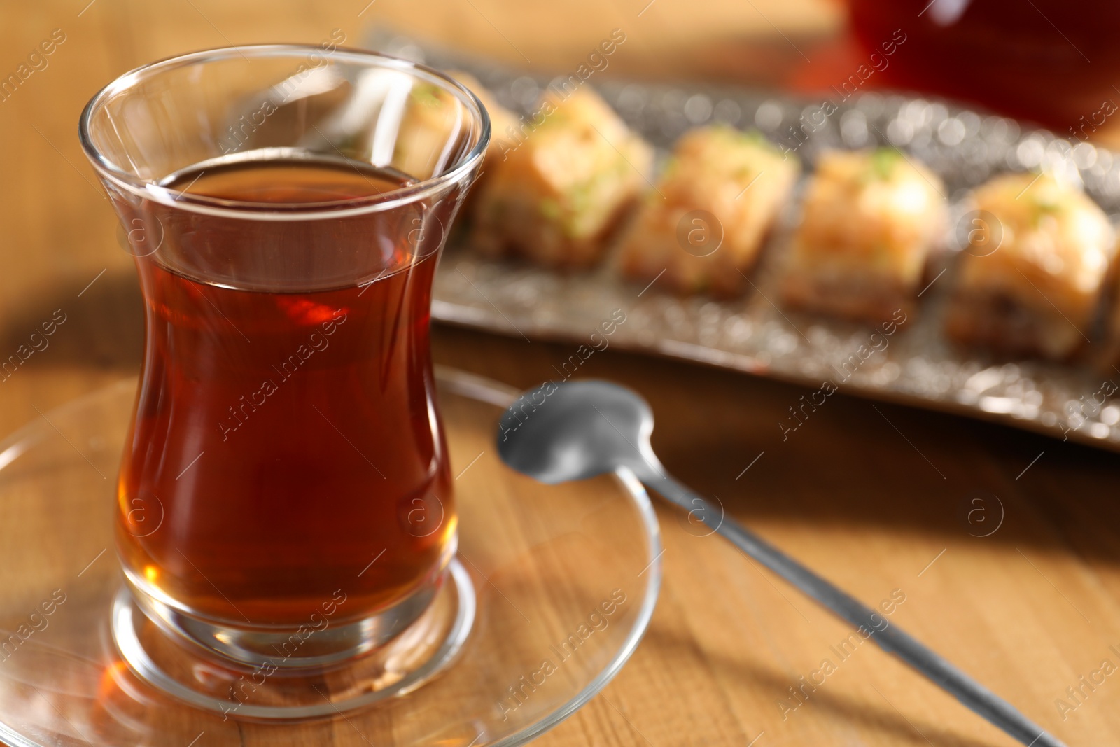 Photo of Traditional Turkish tea in glass on wooden table, closeup. Space for text