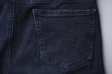 Jeans with pocket on grey background, top view