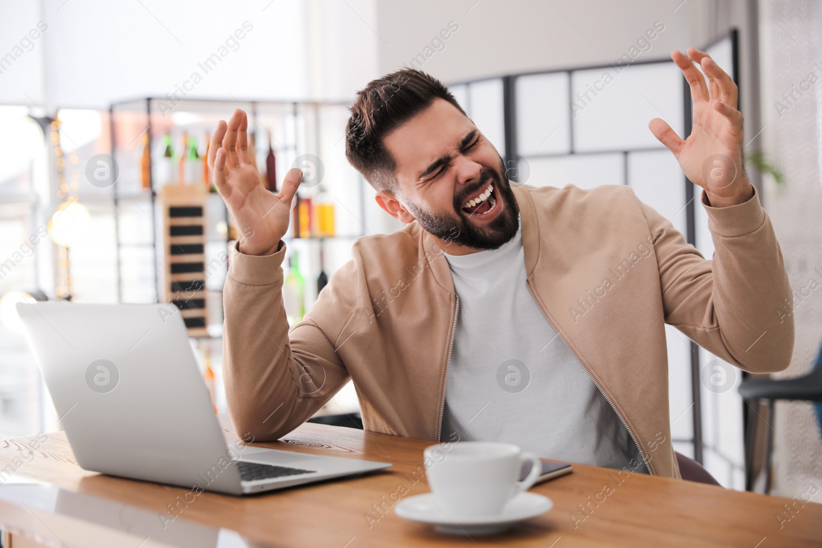 Photo of Emotional young man working on laptop in office. Online hate concept