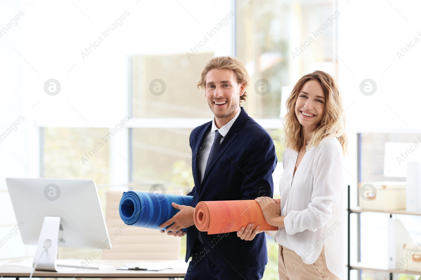 Photo of Young businessman and businesswoman holding yoga mats in office. Gym after work