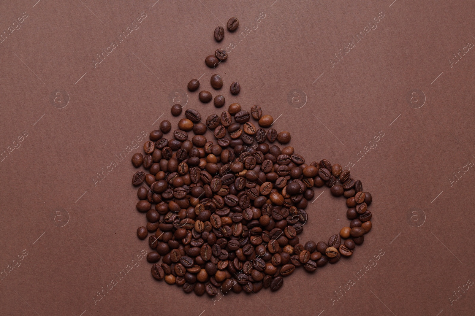 Photo of Cup made of coffee beans on brown background, top view