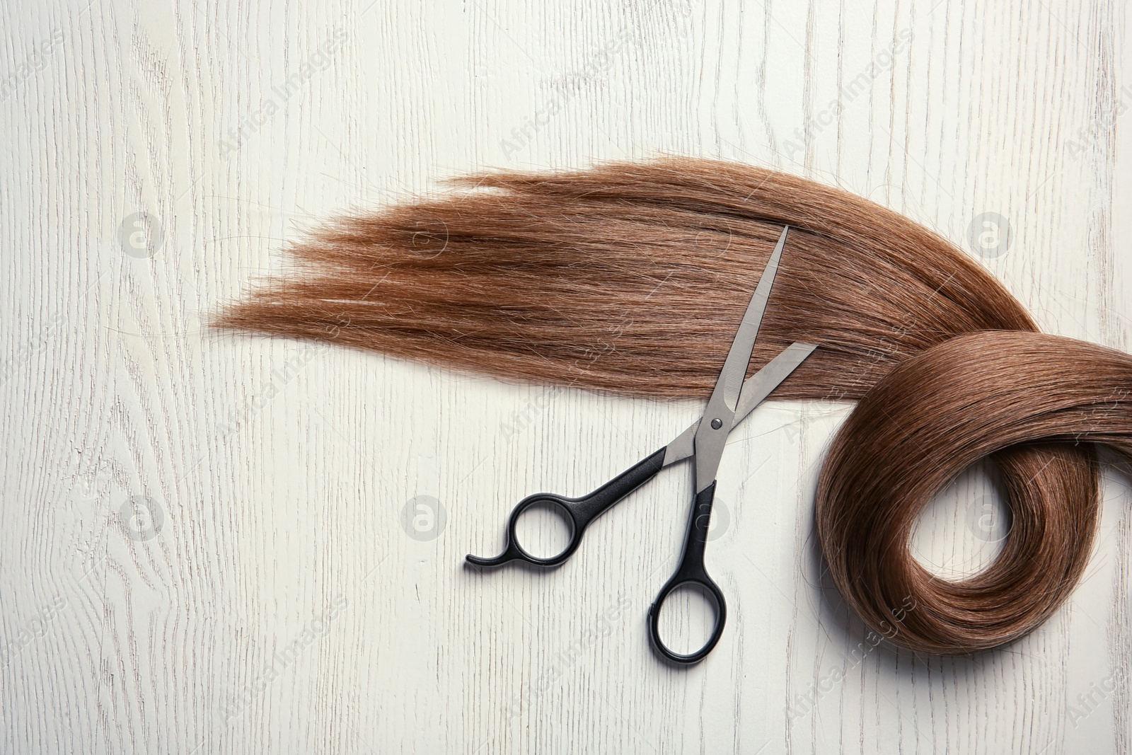 Photo of Composition with lock of brown hair on wooden background, top view