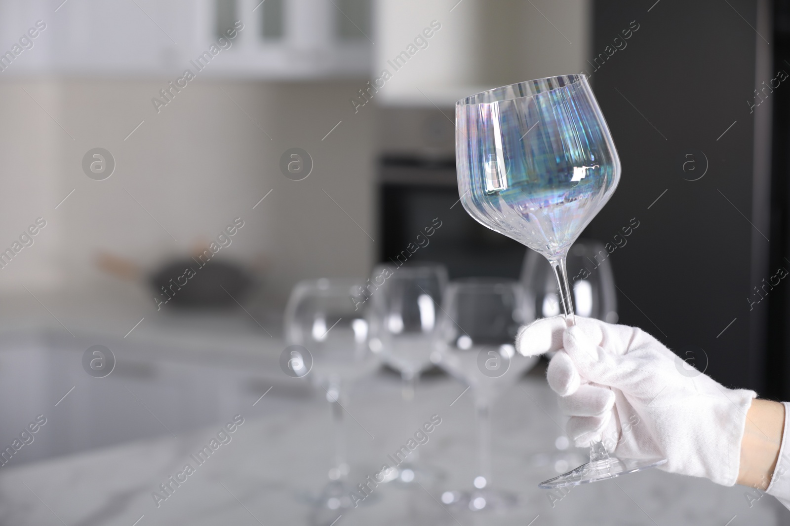 Photo of Person in white glove checking cleanliness of glass indoors, closeup. Space for text