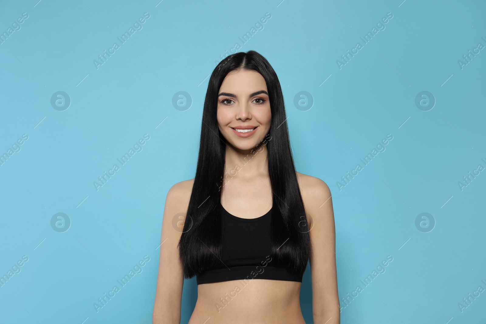 Photo of Beautiful young woman with long straight hair on light blue background
