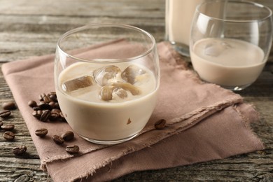 Photo of Coffee cream liqueur in glasses and beans on wooden table, closeup