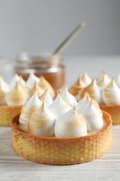 Tartlets with meringue on white wooden table, closeup. Tasty dessert
