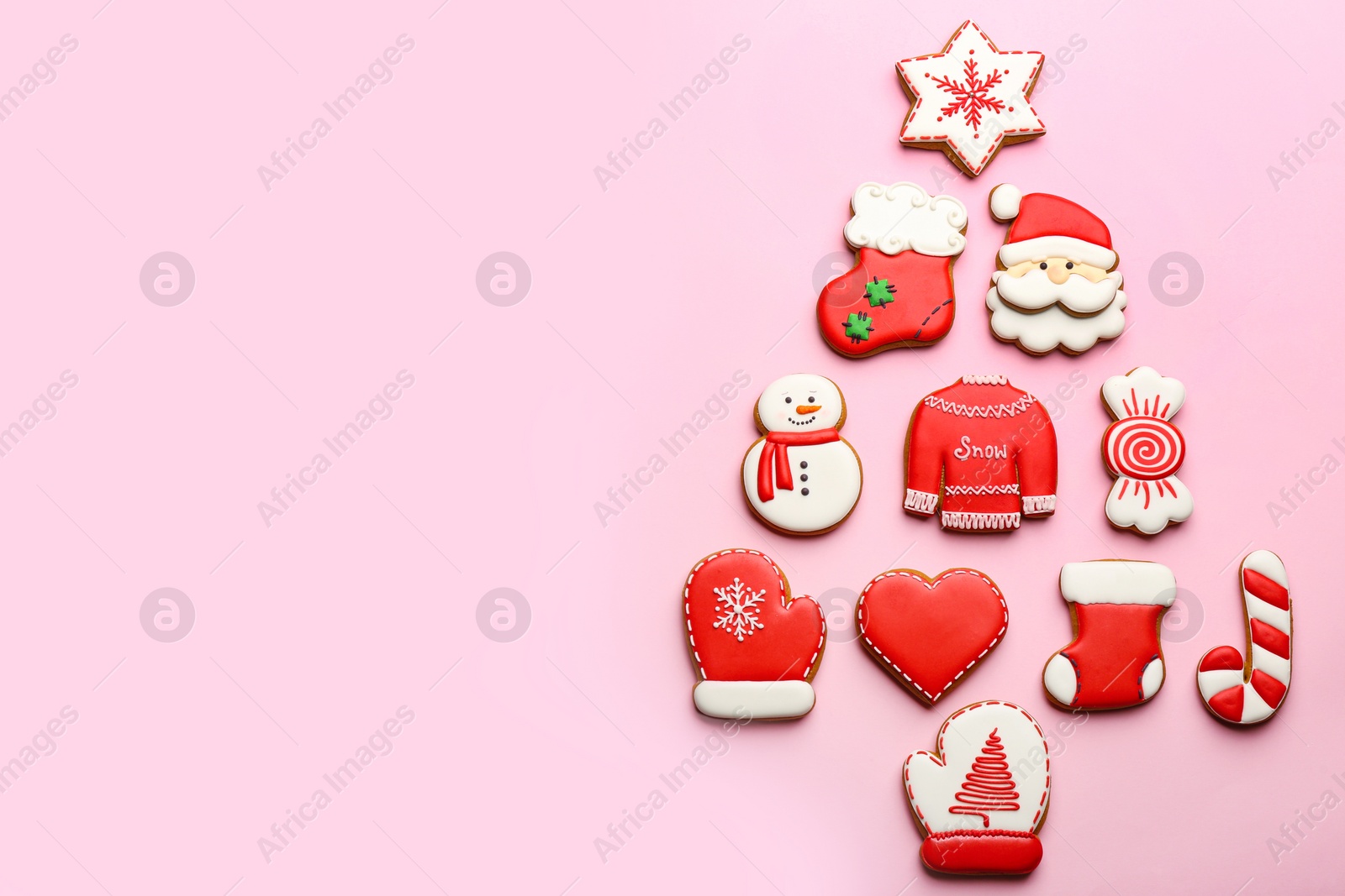 Photo of Delicious gingerbread cookies arranged in shape of Christmas tree on pink background, flat lay. Space for text